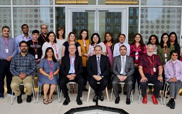 Teacher Educator Graduates with their faculties posing for a group photo with red ID cards around their neck on the first floor of Aga Khan Centre (AKC)