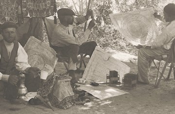 Some men working in a forest ground analysing an enlarged piece of document that looks like a circular design