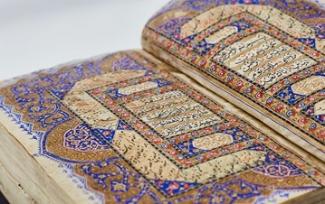 Two sided display of colourful Quran pages displayed verses in Arabic with red, blue and khaki coloured designs around them