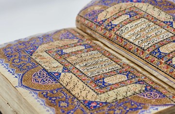 Two sided display of colourful Quran pages displayed verses in Arabic with red, blue and khaki coloured designs around them