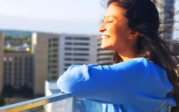 A girl in sky blue hoody smiling and looking away