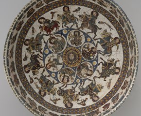 A round dish with diverse colour combinations and humans, animals and geometric designs painted inside of it 