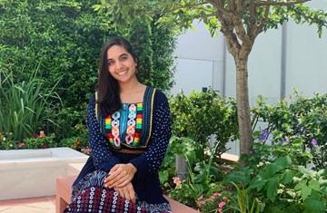 Anum Ameen Hossain sitting in a garden at AKC and posing for a picture