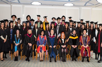 Cohort 12 graduates taking a group photo with the faculties and dignitaries all dressed in graduation gowns on the convocation day