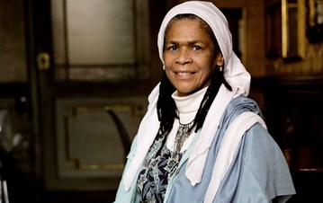 An image of Amina wadud sitting on a chair and posing