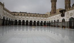 An open space in a mosque surrounded by arches on all three sides of it.