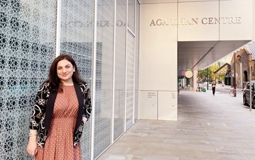 STEP student Fariza Sheralieva in a peach dress and black cardigan standing outside of Aga Khan Centre and posing for a picture 