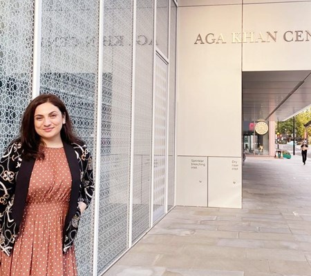 STEP student Fariza Sheralieva in a peach dress and black cardigan standing outside of Aga Khan Centre and posing for a picture 