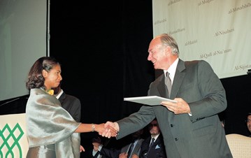 A GPISH graduate smiling and shaking hands with AgaKhan IV handing over a certificate to her