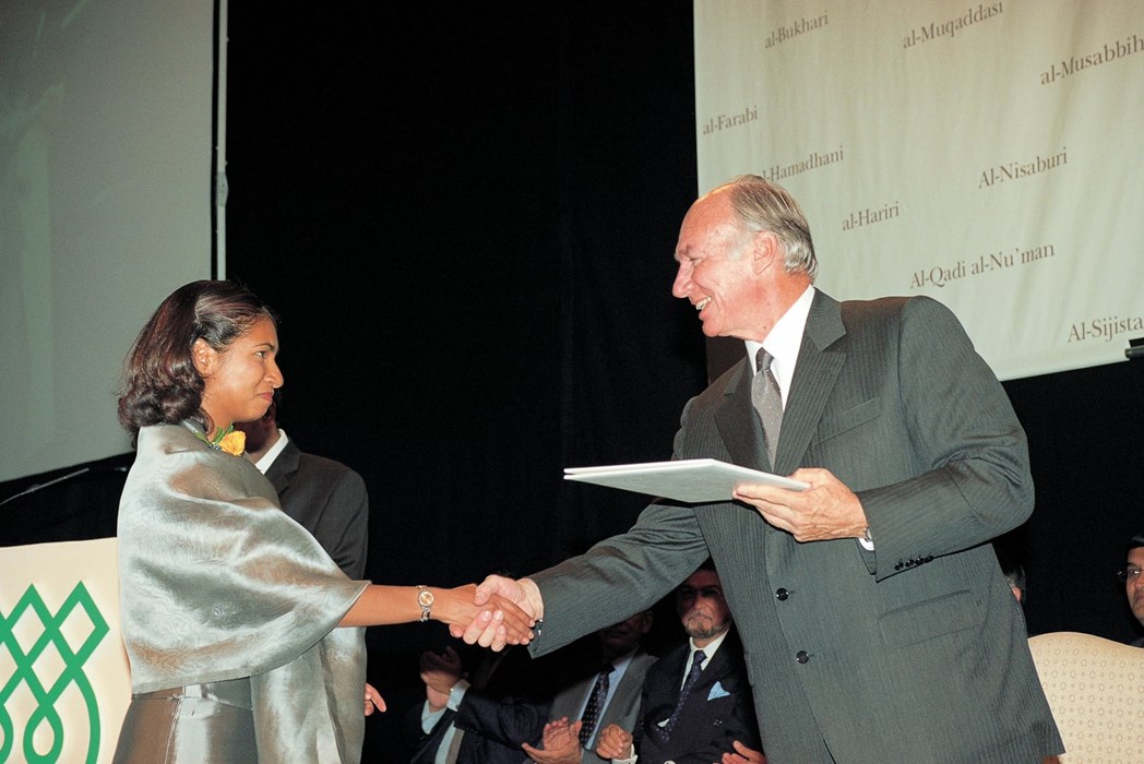 A GPISH graduate smiling and shaking hands with AgaKhan IV handing over a certificate to her