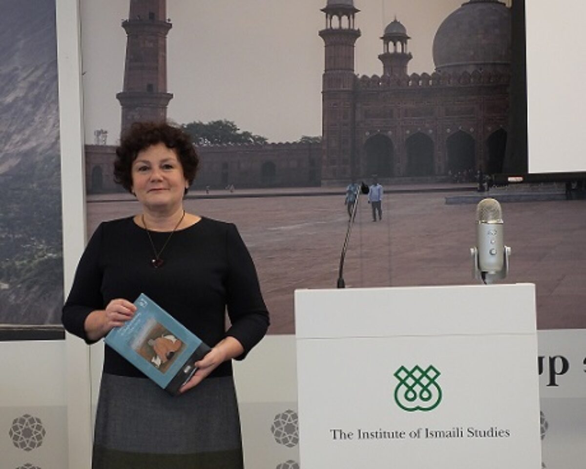 A woman standing with a book in her hand next to a podium with IIS logo