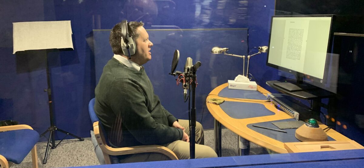 A side view of Dr Stephen Burge, reporting an audiobook on Prophet Muhammad from the recording studio