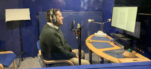 A side view of Dr Stephen Burge, reporting an audiobook on Prophet Muhammad from the recording studio
