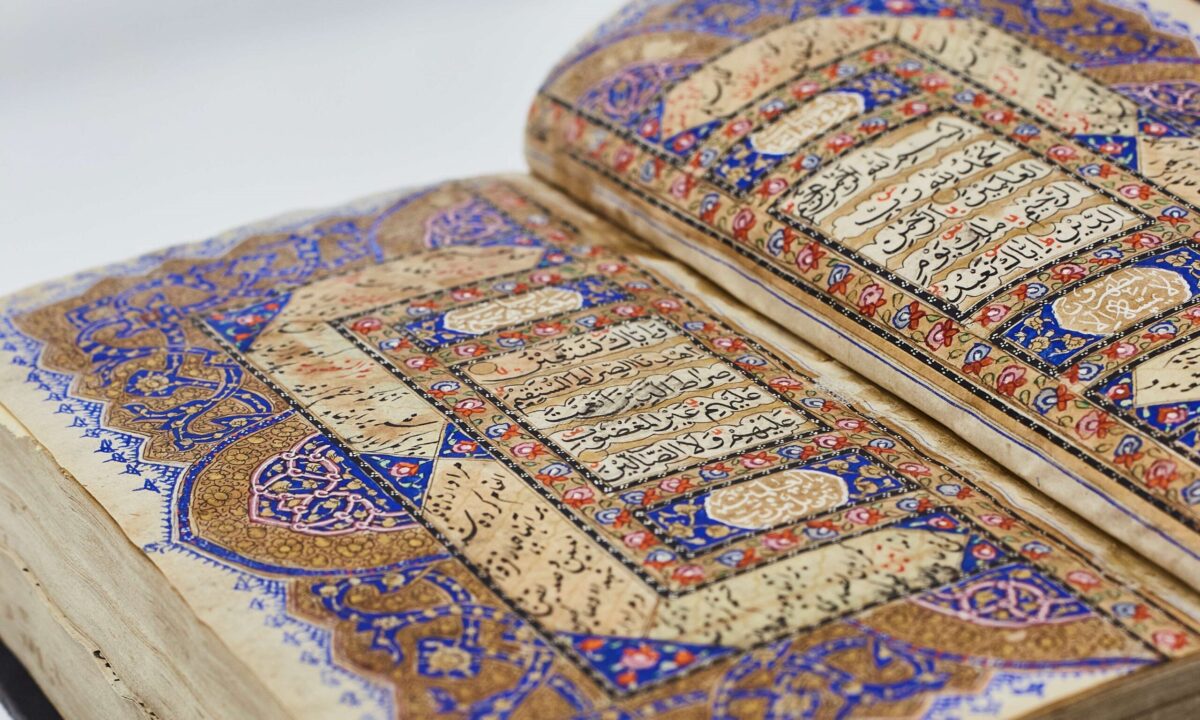 Two sided display of colourful Quran pages displayed verses in Arabic with red, blue and khaki coloured designs around them