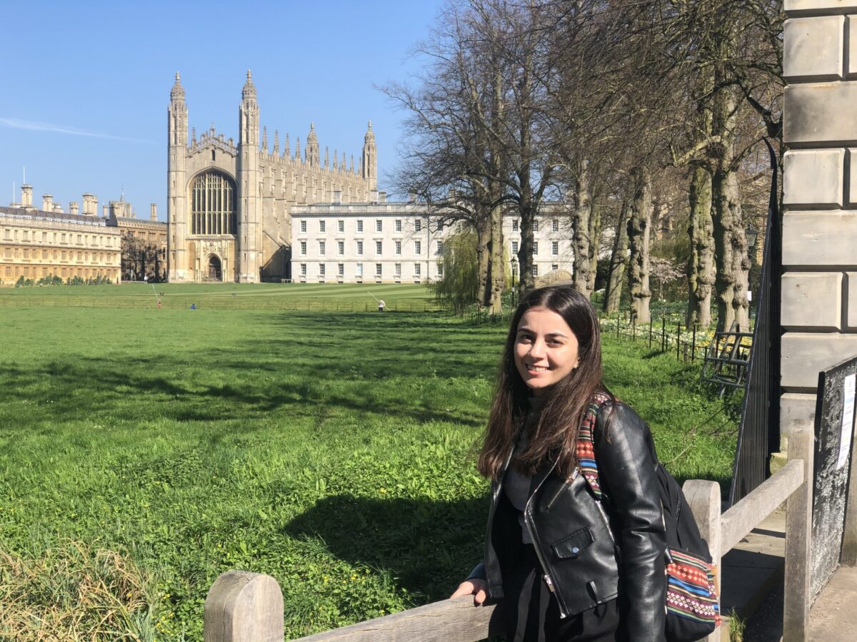 A STEP student named Mizhgona Okhonniyozo in black leather jacket and a backpack standing near a European building and posing for a picture