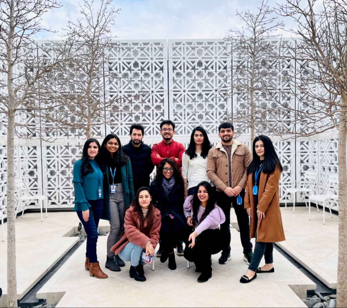 STEP C14 students standing in a group with Farah Elaha (IIS faculty) in the centre posing for a picture in the terrace of Aga Khan Centre (AKC)