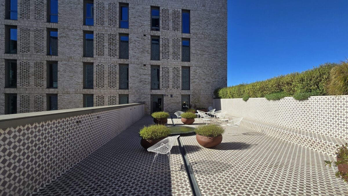 Tiled garden terrace at Victoria Hall with terracotta planters, a small circular pool and white wire chairs.