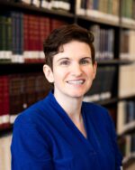 Emily Turnner in blue shirt, library background.