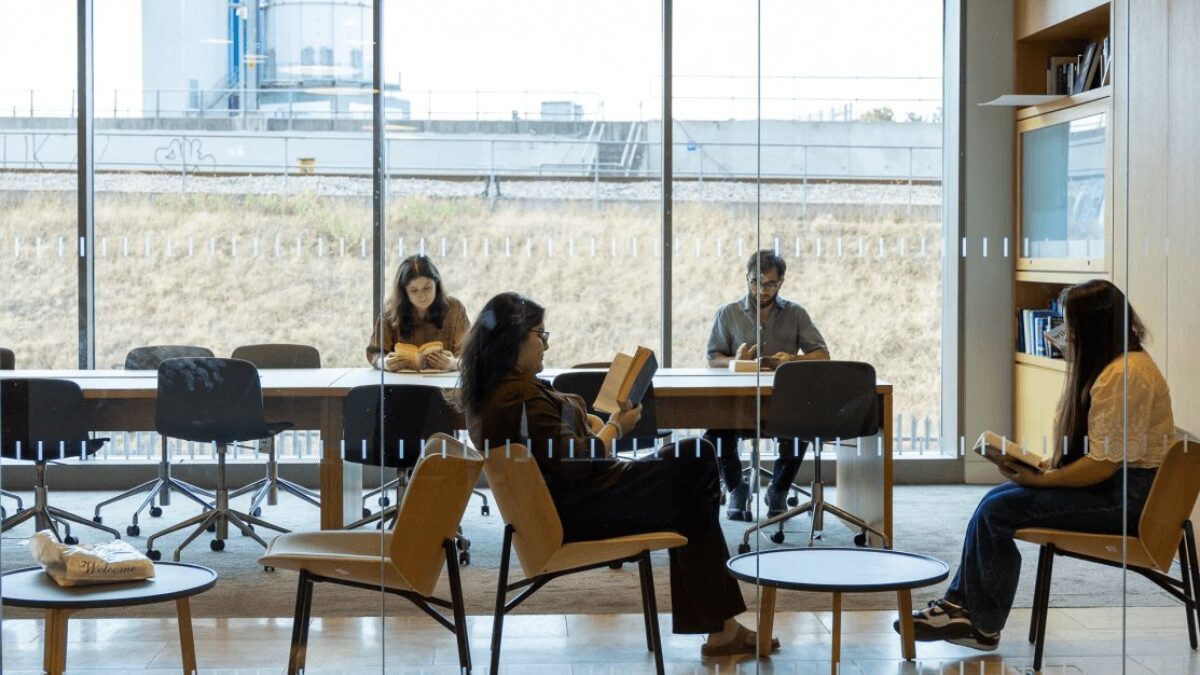Four GPISH students read at a long table and in lounge chairs in the reading room at Victoria Hall.