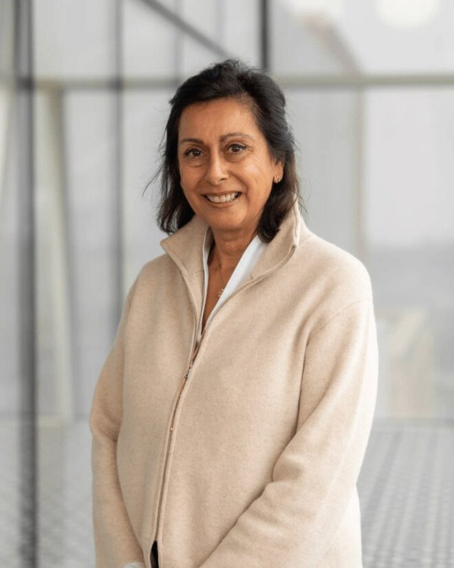 Nadia Eboo Jamal, IIS Governor, smiling in a cream zip-up knit jacket over a white shirt.