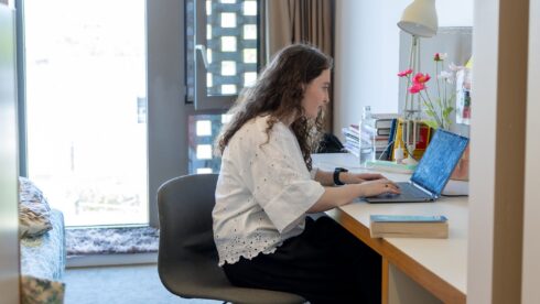 Sabahat, a STEP C18 student, working on a laptop in her Victoria Hall accommodation room.