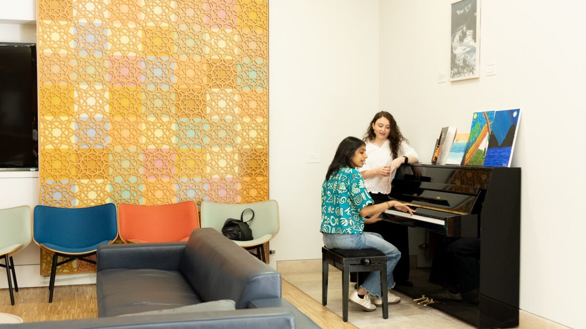 STEP students at a piano in the student lounge.