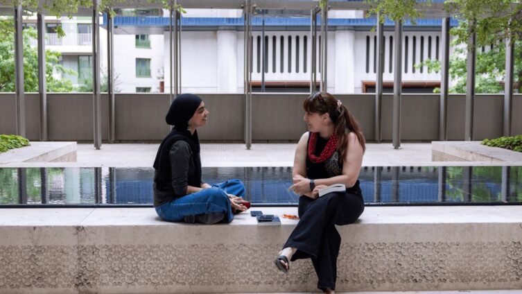 GPISH students Anila Goulamhussen and Shenida Sultana talk beside a reflecting pool in the first-floor garden at Victoria Hall.