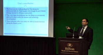 A man in a suit presenting something on a projector