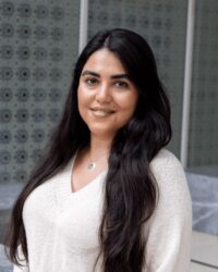 Elnaz Basri, GPISH student, smiling in front of a geometric patterned screen.