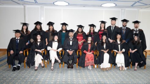 STEP Cohort 17 graduates in academic gowns at a graduation ceremony at the Ismaili Centre.