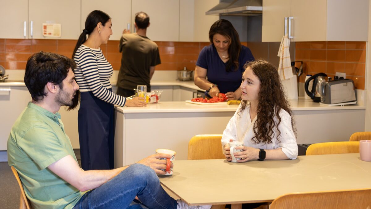 STEP students preparing food and talking in a shared kitchen.