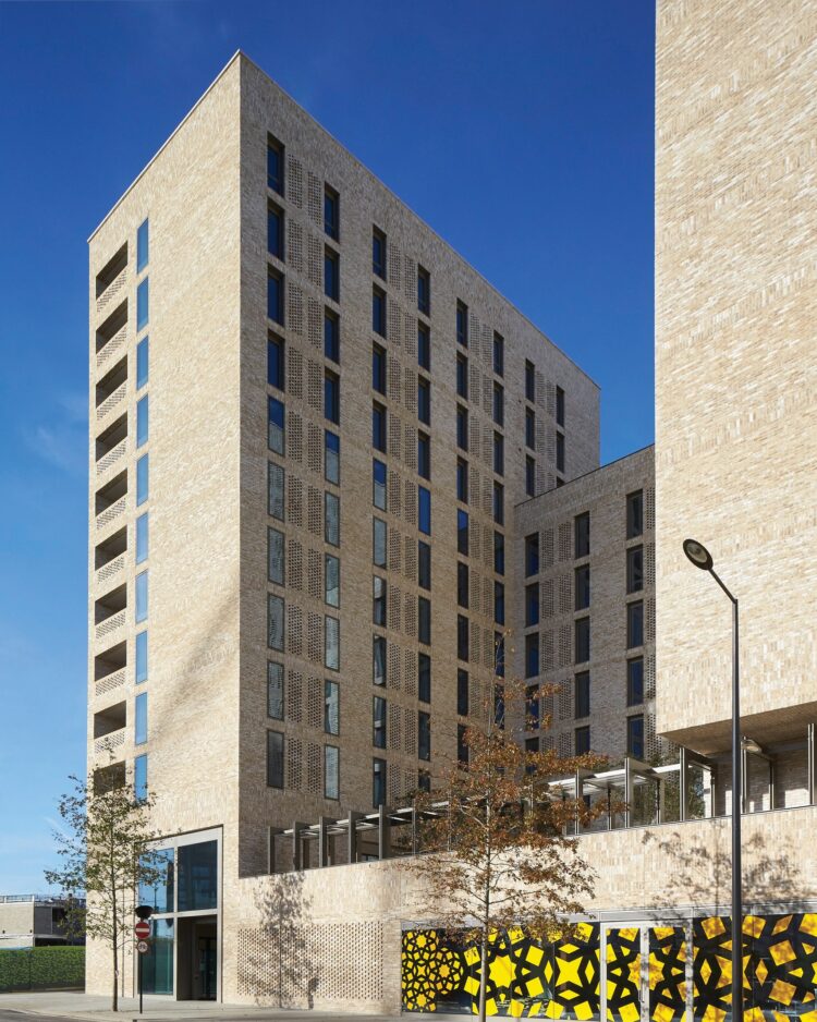 Tall brick building with patterned brickwork and geometric yellow-and-black screens at street level.