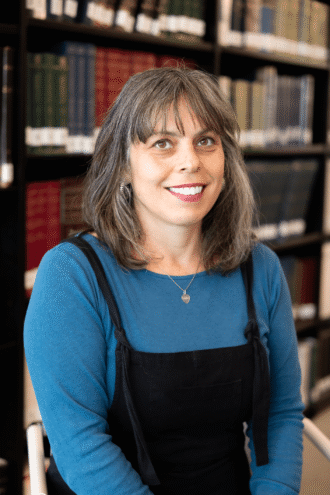 a woman smiling in front of a bookshelf