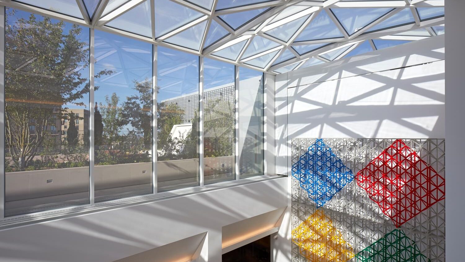 a glass ceiling with a colorful wall and a wall with a tree in the background