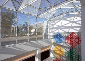 a glass ceiling with a colorful wall and a wall with a tree in the background
