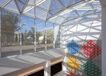 a glass ceiling with a colorful wall and a wall with a tree in the background