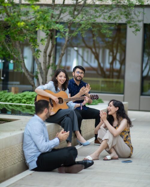 a group of people sitting on a bench playing guitar