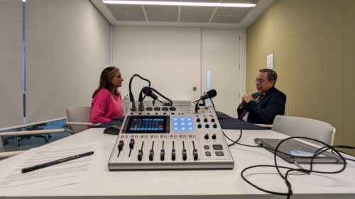 a man and woman sitting at a table with a microphone