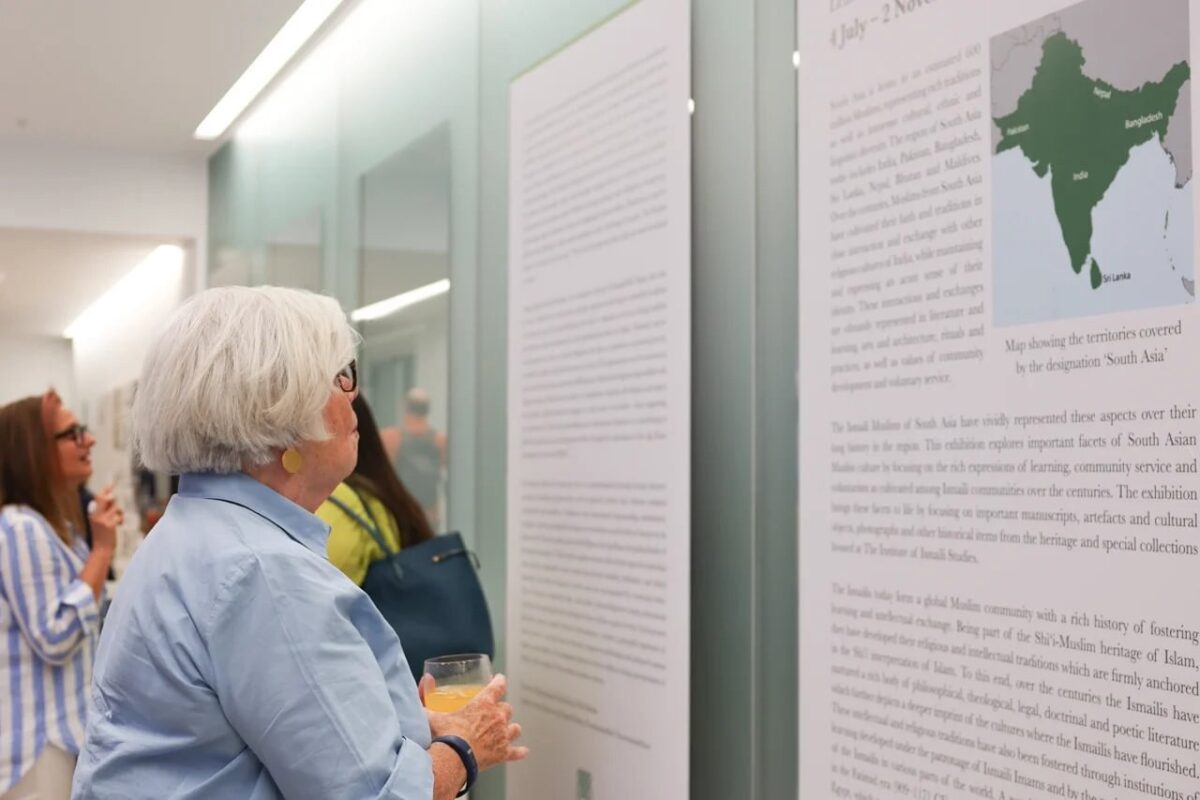 A visitor stands in front of large informational panels at the exhibition, including a map of South Asia. The panels contain detailed text and visuals.
