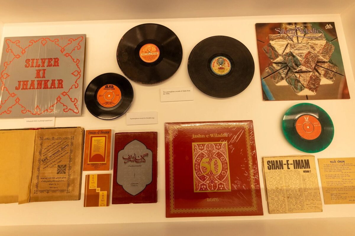 A collection of vinyl records, record covers, and booklets displayed on a flat surface. Items include “SILVER KI JHANKAR,” “Silver Jubilee,” “SHAN-E-IMAM,” and “Jashn-e-Wiladat.” Labels are placed near some items.
