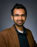 Man in brown jacket, neutral background.
