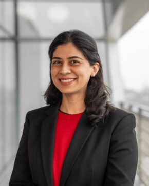 Professor Shenila Khoja-Moolji, IIS Governor, smiling in a black blazer over a red top.