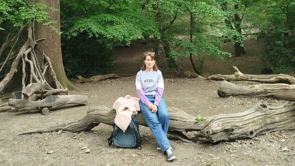 Nairouz Razouq seated on a trunk during the STEP workshop in Queen's Wood.