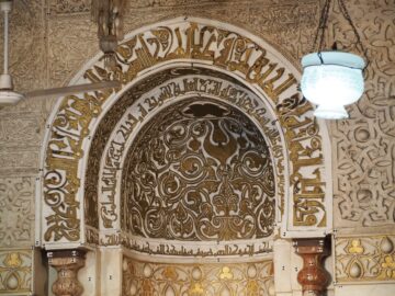 A carved stucco niche with an arched hood and inscription bands at al-Azhar Mosque, Cairo.