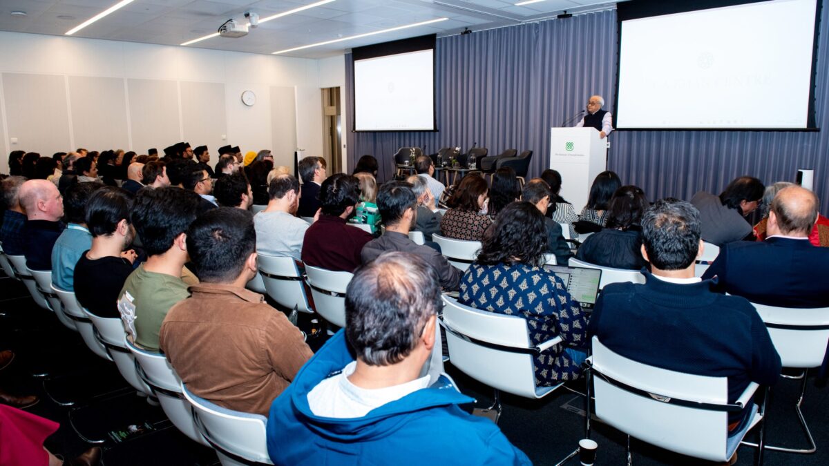 Jay Visvadeva addressing a seated audience from a lectern at the Aga Khan Centre.
