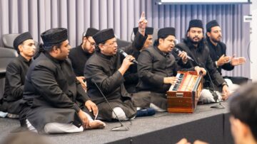 The Warsi Brothers and their qawwali group performing on stage at the Aga Khan Centre, with a harmonium in view.