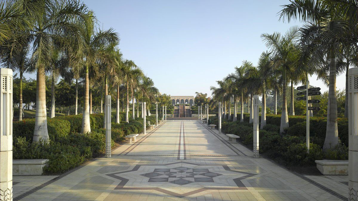 Palm-lined stone promenade with a star-patterned paving medallion leading to an arcaded pavilion at Al-Azhar Park, Cairo.