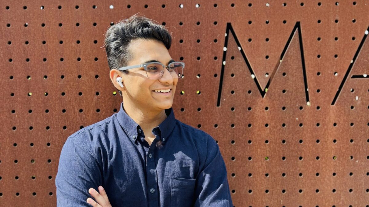 Muhammad Ali Sohail smiling outdoors in front of a rust-coloured perforated metal wall.