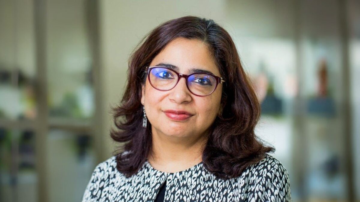 Professor Tashmin Khamis, head-and-shoulders portrait, wearing glasses and a patterned top.