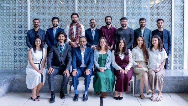 Group of Imagine Future conference participants seated and standing before a patterned glass screen at the Aga Khan Centre.
